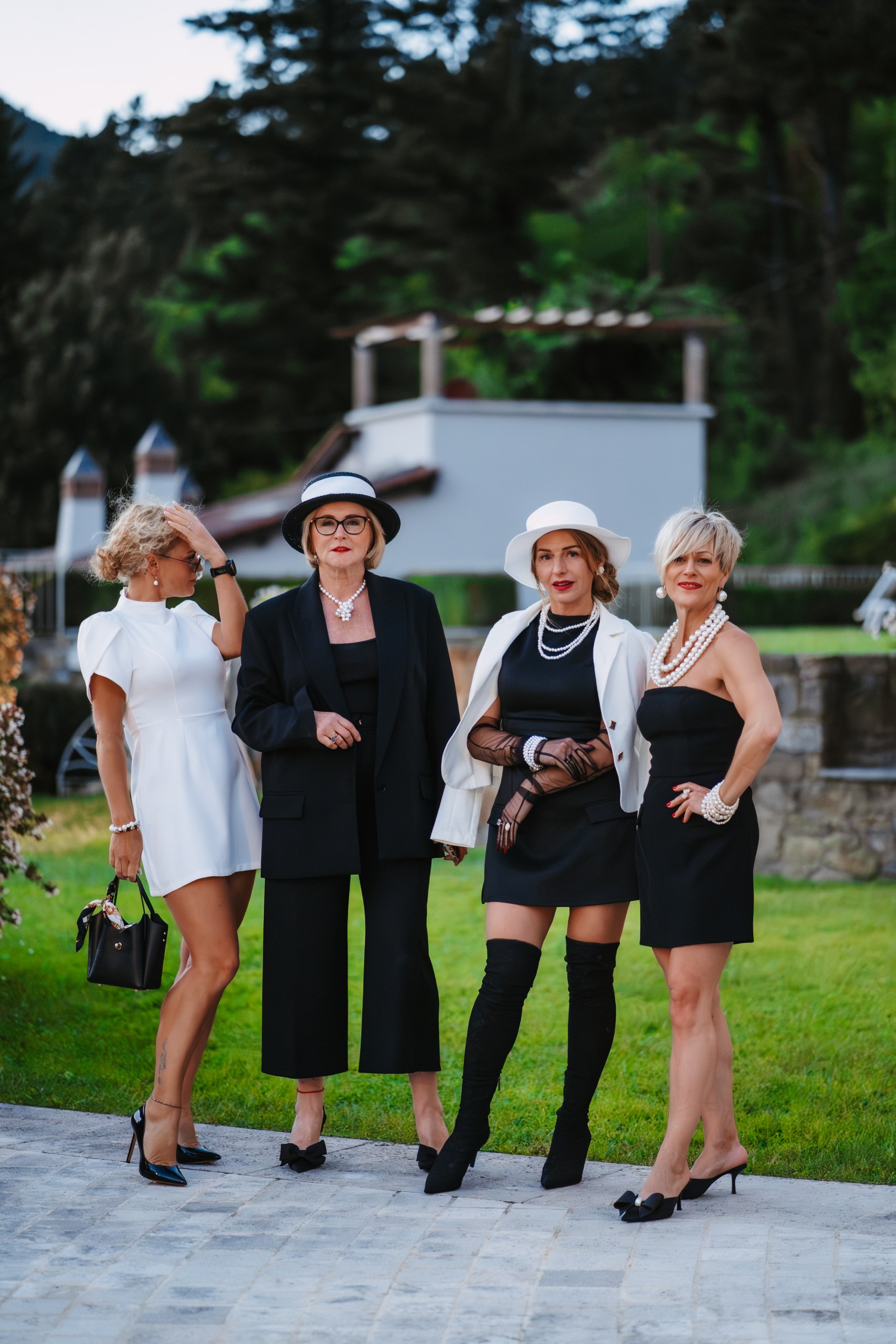 Four guests in individual black-and-white outfits with pearl jewellery