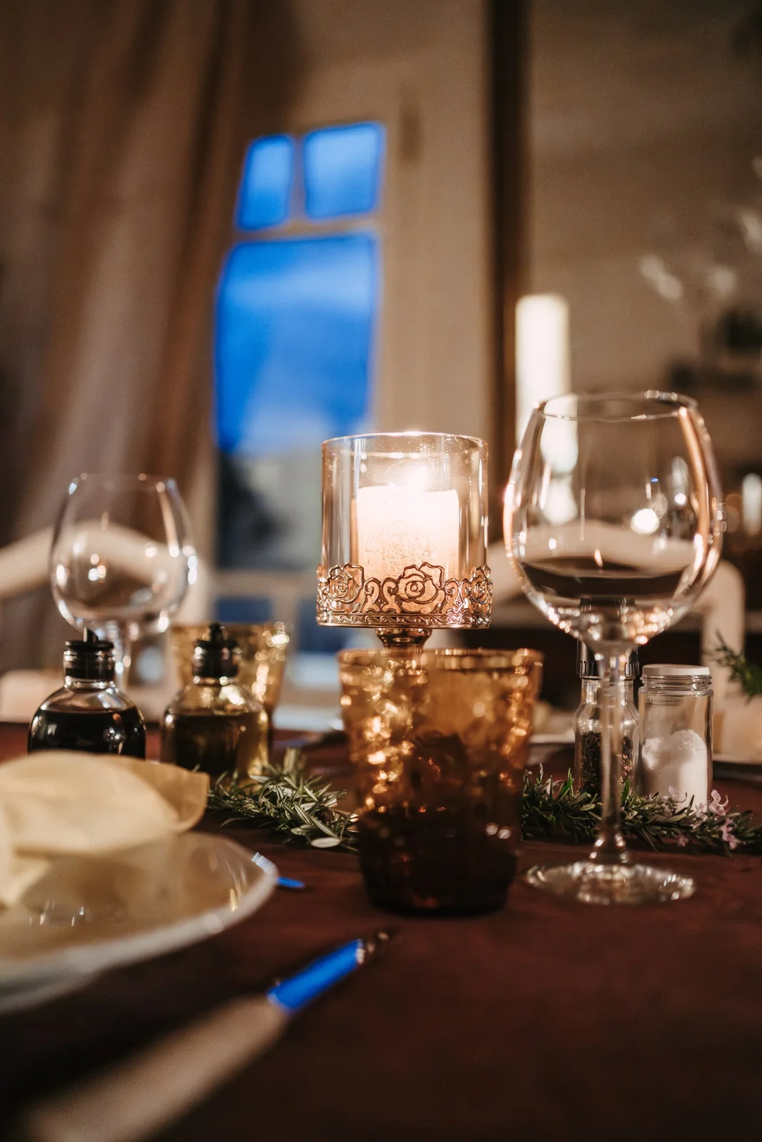 Warm candlelight, a wine glass and rosemary on a celebration table