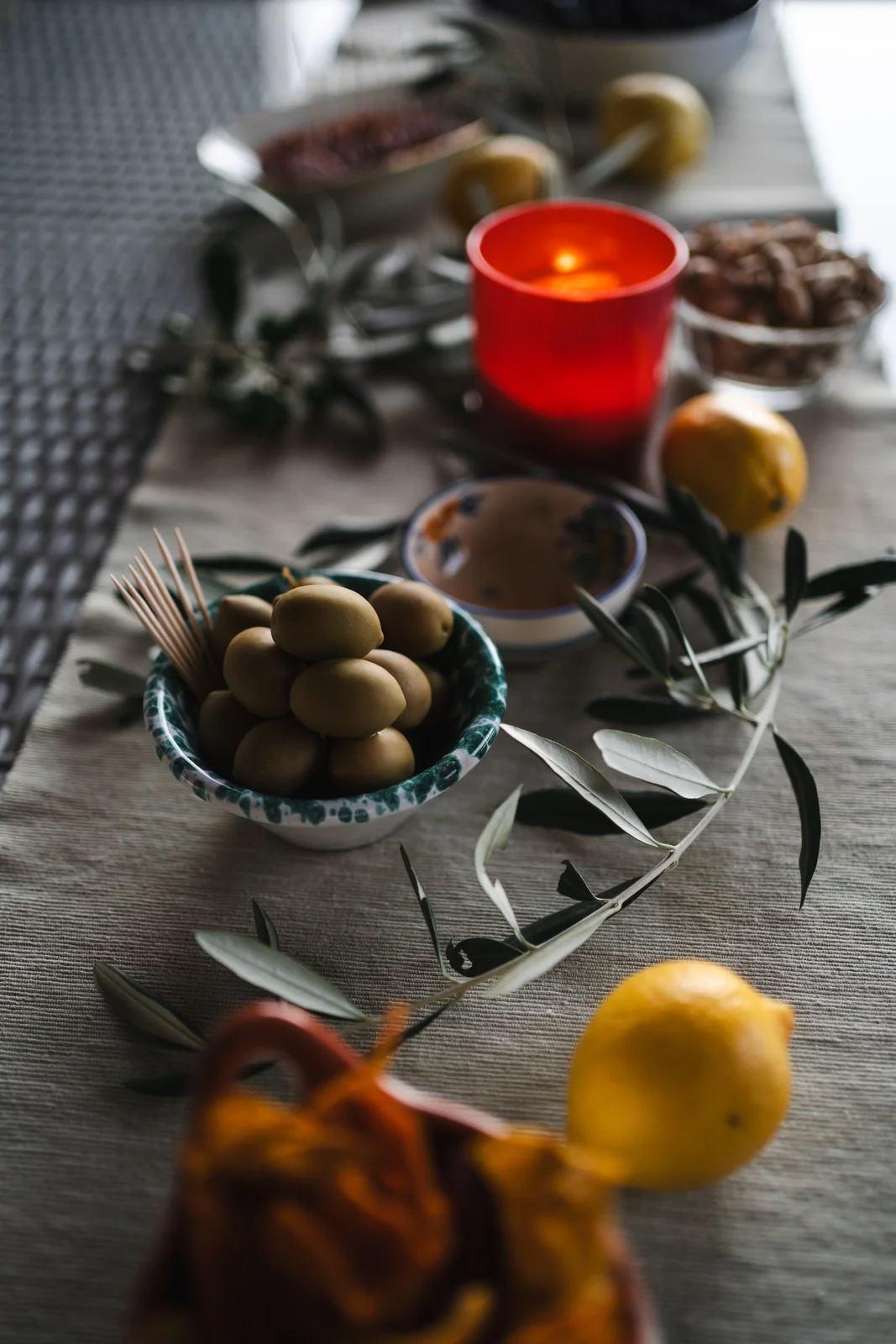 Olives, lemons, olive branches and a red candle on a celebration table