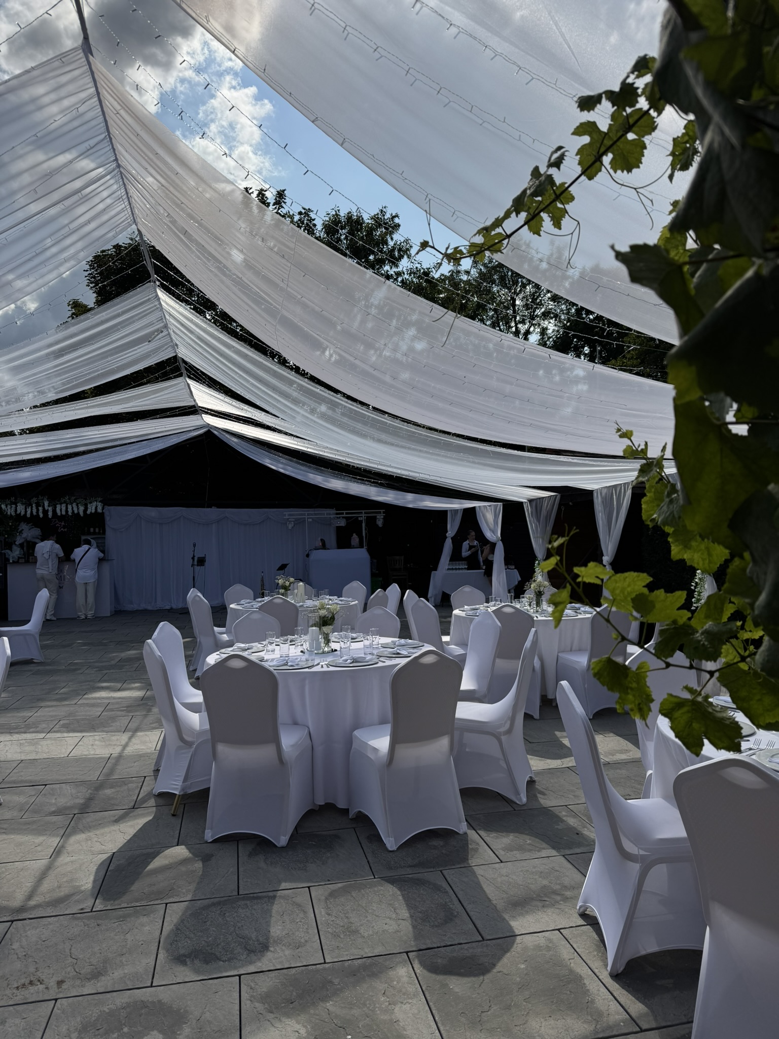 An outdoor celebration setting with white tables and fabric installations